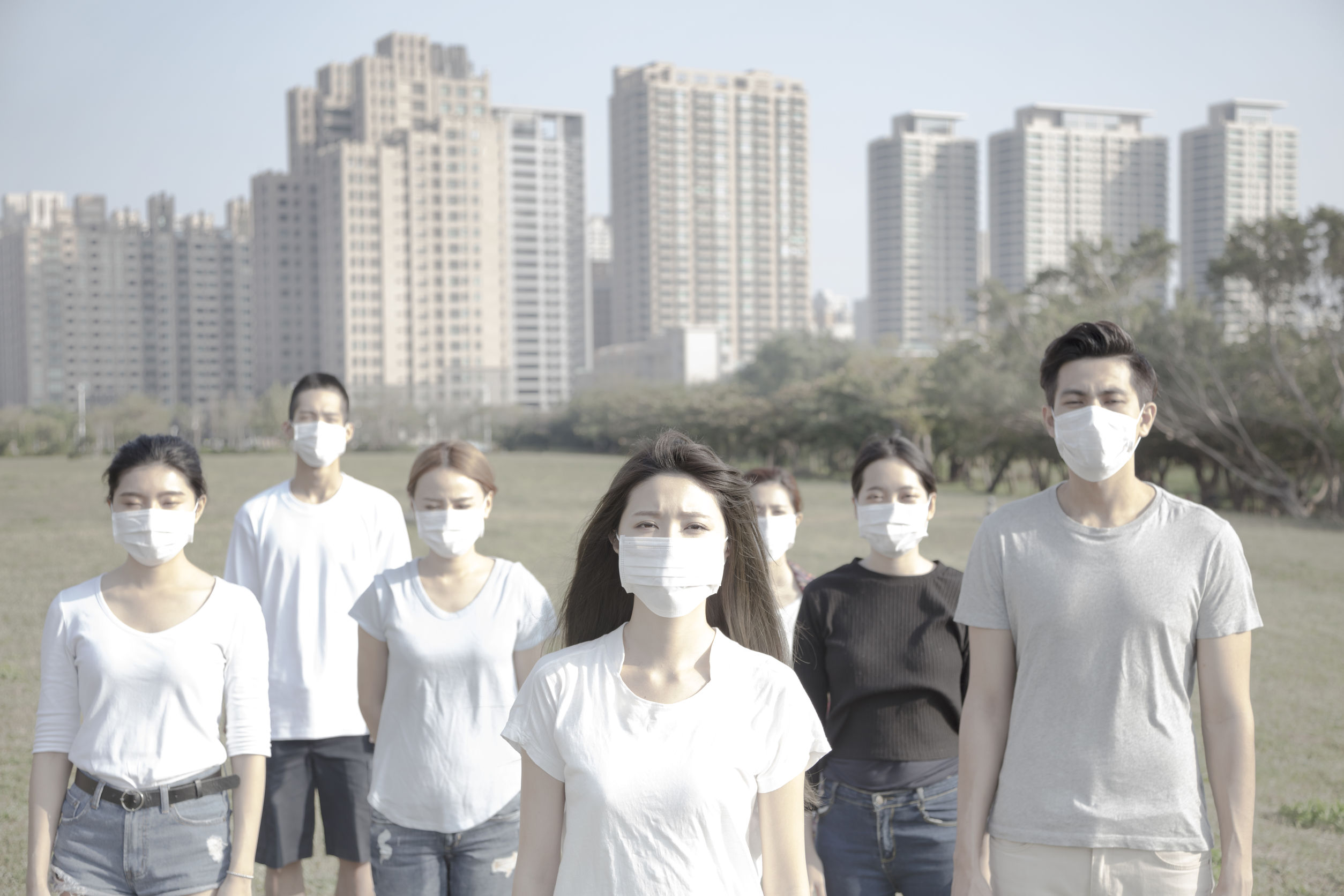 People wearing masks and standing in a park.
